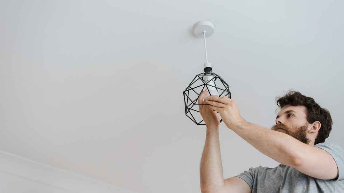 man screwing light bulb into lamp