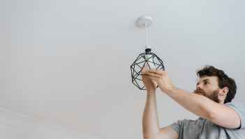 man screwing light bulb into lamp