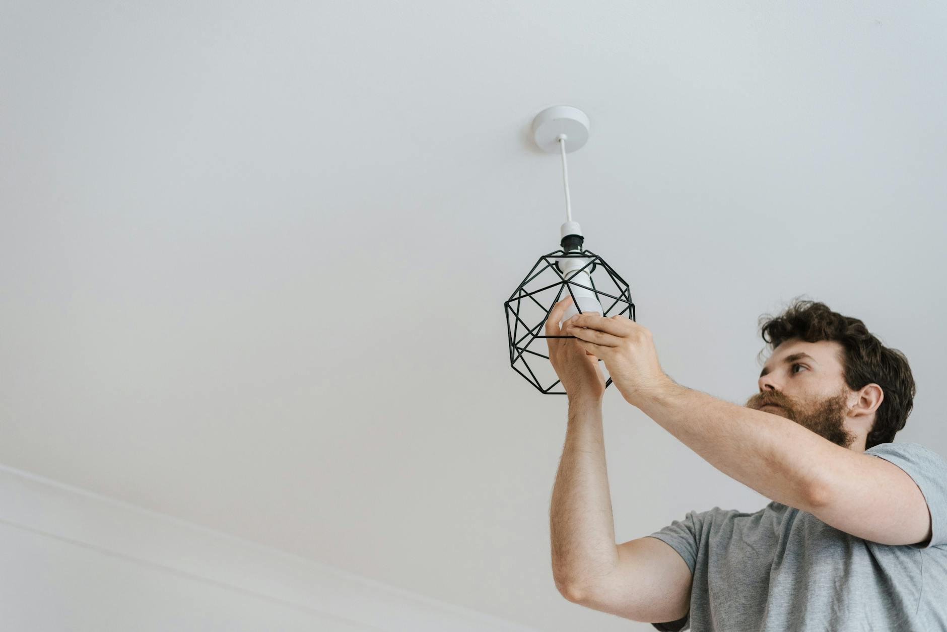 man screwing light bulb into lamp